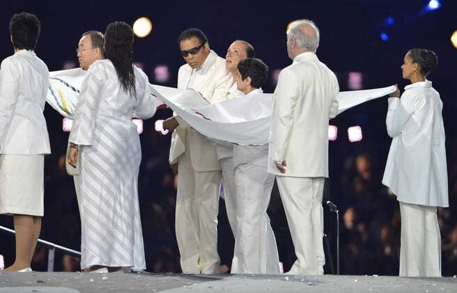 back (L-R) Ban Ki Moon, Muhammad Ali (C) with wife Lonnie, Shami Chakrabarti, Marina Silva - front: Sally Becker, Leymah Gbowee, Daniel Barenboim carrying the Olympic flag during the opening ceremony of the London 2012 Summer Olympics, July 27, 2012, in Stratford, London. The ceremony, welcoming more than 10,000 athletes from 204 nations, were a celebration of the hundreds of years of British history and culture. OLY20120727501