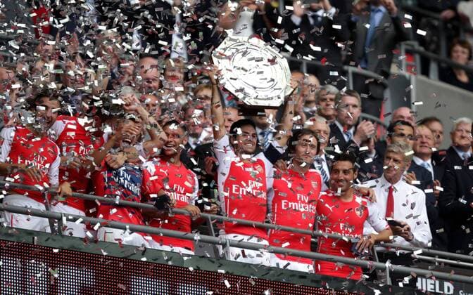 FA Community Shield - Arsenal v Manchester City . . Wembley, Middlesex, UK . . 10.08.2014 Mikel Arteta (A) lifts the Community Shield as Arsene Wenger (Arsenal manager) smiles.