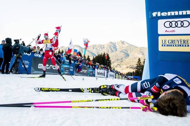 190106 Sergey Ustiugov of Russia cross the finnish line while Johannes Hosflot Klaebo of Norway lies down during men s finale climb on January 6 2019 in Val di Fiemme Photo Fredrik Varfjell BILDBYRAN kod FV 150204, detectedSourceLanguage  Copyright: FREDRIKxVARFJELL BB190106FV044