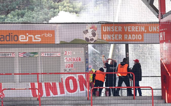 Football, men, 2020 2021 season, 1 Bundesliga 27 matchday , 1 FC Union Berlin Hertha BSC, after setting off fireworks, the roof of a snack bar on the forest side is on fire, stewards try to put out the fire, 04 04 2021, Copyright: xMatthiasxKochx