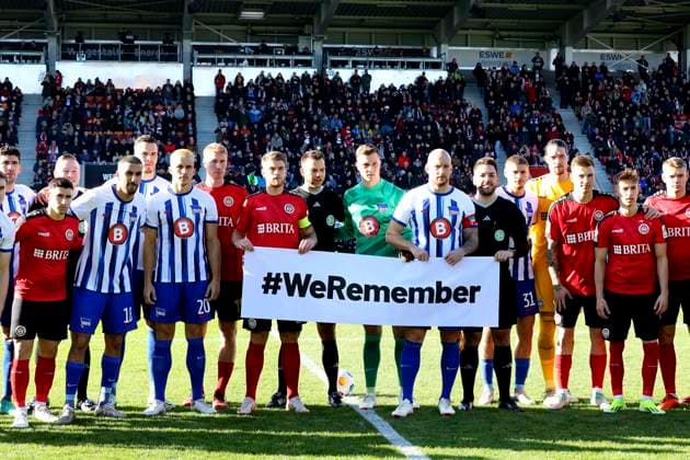 27 01 2024, xavx, Soccer 2 Bundesliga, SV Wehen Wiesbaden Hertha BSC Berlin emspor, v l Players of both teams with a banner with the inscription WeRemember in memory of the victims of National Socialism DFL DFB REGULATIONS PROHIBIT ANY USE OF PHOTOGRAPHS as IMAGE SEQUENCES and or QUASI VIDEO Wiesbaden