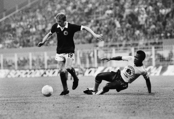 Football - 1974 World Cup - First Round, Group Two: Scotland 2 Zaire 0 Scotland s Denis Law evades a tackle from Zaire s Buanga Tshimen at Westfalenstadion, Dortmund, West Germany.