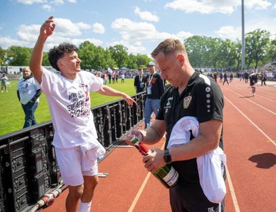 Soccer, Men, Season 2024 2025, COSY WASCH Berlin State Cup Final at Mommsenstadion, BSV Eintracht Mahlsdorf BFC Dynamo 0 2 , Coach Dennis Kutrieb BFC Dynamo opens a bottle of champagne for Henry Jon Crosthwaite BFC Dynamo, cheering after the final whistle, 24 05 2025, Copyright: xMatthiasxKochx
