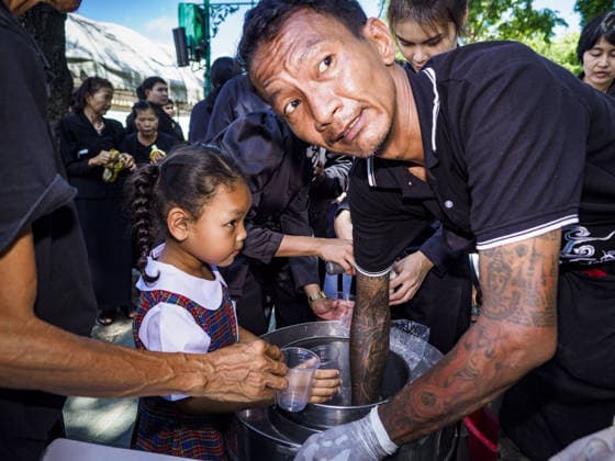 September 27, 2017 - Bangkok, Bangkok, Thailand - A volunteer serves ice cream to people waiting to pay respects to the funeral urn of the Late King at the Grand Palace in Bangkok. Bhumibol Adulyadej, the Late King of Thailand, died on October 13, 2016. Thailand has been in a state of mourning since. He will be cremated on October 26, 2017. Thais have been going to the Grand Palace to pay respects to the revered King. The Thai government has announced that the palace will close to the public on October 4, 2017, to prepare for the Monarch s funeral. Since the announcement, tens of thousands of Thais have lined up at the palace every day to pay their final respects. Copyright: xSeanxEdisonx