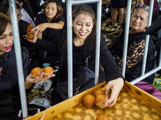 September 27, 2017 - Bangkok, Bangkok, Thailand - Women waiting to pay final respects to the funeral urn of the Late King pass out muffins donated to the crowd by a local bakery. Bhumibol Adulyadej, the Late King of Thailand, died on October 13, 2016. Thailand has been in a state of mourning since. He will be cremated on October 26, 2017. Thais have been going to the Grand Palace to pay respects to the revered King. The Thai government has announced that the palace will close to the public on October 4, 2017, to prepare for the Monarch s funeral. Since the announcement, tens of thousands of Thais have lined up at the palace every day to pay their final respects. Copyright: xSeanxEdisonx