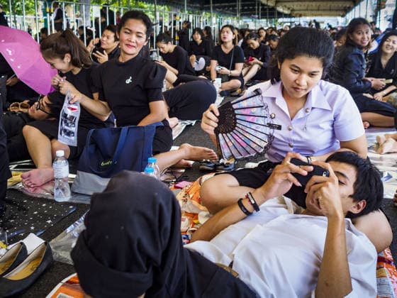 September 27, 2017 - Bangkok, Bangkok, Thailand - A girl fans herself and her friend while they wait to get into the Grand Palace to pay respects to the funeral urn of the Late King. Bhumibol Adulyadej, the Late King of Thailand, died on October 13, 2016. Thailand has been in a state of mourning since. He will be cremated on October 26, 2017. Thais have been going to the Grand Palace to pay respects to the revered King. The Thai government has announced that the palace will close to the public on October 4, 2017, to prepare for the Monarch s funeral. Since the announcement, tens of thousands of Thais have lined up at the palace every day to pay their final respects. Copyright: xSeanxEdisonx
