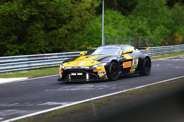 The black and yellow Aston Martin Vantage GT3 with the starting number 169 of the Doerr Motorsport team drives through a corner on the Nordschleife at the ADAC RAVENOL 24h Nürburgring 2026 The car Heiko Hahn Philippe Charlaix Roland Waschkau Doerr Motorsport wears eye-catching yellow and black Pirelli sponsoring livery and is marked with Pirelli , RAVENOL , DEKRA and H R logos The characteristic crash barriers and the lush green of the Eifel can be seen in the background Aston Martin 169 on the Nordschleife at the 24h Nürburgring 2026 Copyright: xspeedshotx