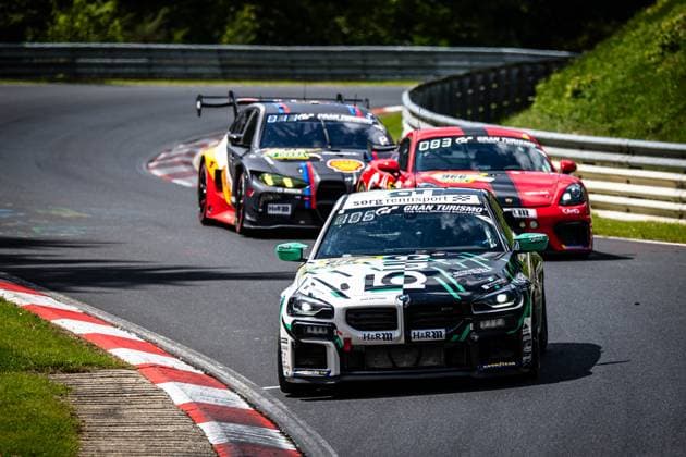Exciting group race on the Nordschleife of the Nürburgring at the ADAC RAVENOL 24h Nürburgring 2026 In the foreground, a black and white BMW M2 with the starting number 966 and Sorg Rennsport lettering as well as Gran Turismo sponsoring leads the group Behind it follows a dark matt gray BMW with Shell and DEKRA sponsoring, as well as a red sports car with the number 083 and another red vehicle with the number 966 in the background The vehicles drive through a bend on the characteristic asphalt of the Nordschleife with typical red and white curbs Jan Niklas Stieler Kim Berwanger Leonhard Oehme Moritz Oehme René Höber asBest Racing leads the field in this thrilling motorsport moment Multi-vehicle group on the Nordschleife at the 24h Nürburgring 2026 Copyright: xspeedshotx