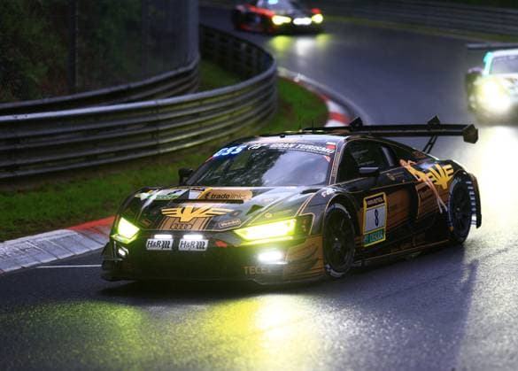 The Alexey Veremenko Elia Erhart Vasilii Selivanov JUTA Racing from JUTA Racing, an Audi R8 GT3 EVO in the striking black and gold livery with sponsors such as RAVENOL, Veedol, H R, tradelinks, TECE and Gran Turismo, battles its way around the wet Nordschleife of the Nürburgring at dusk with its headlights switched on The car with starting number 8 takes a bend, while other vehicles with illuminated headlights can be seen in the background The atmosphere is atmospheric with shiny, damp asphalt and dramatic lighting Audi R8 GT3 8 from JUTA Racing at dusk on the Nordschleife Copyright: xspeedshotx