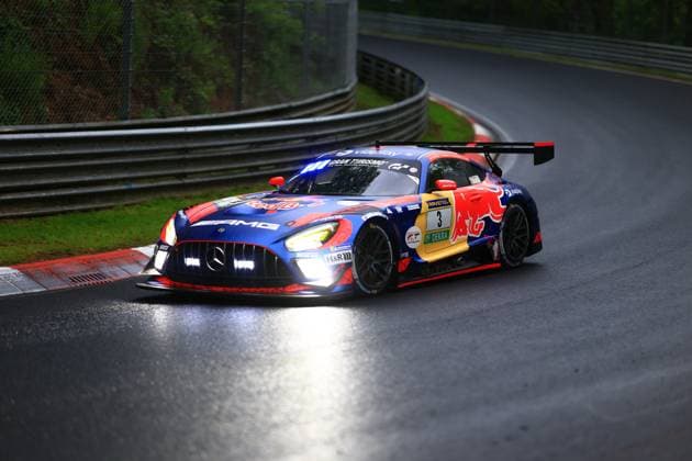 The Mercedes AMG GT3 Daniel Juncadella Jules Gounon Lucas Auer Max Verstappen Mercedes AMG Team Verstappen Racing of the Mercedes AMG Team Verstappen Racing fights its way through a corner on the Nordschleife of the Nürburgring in wet conditions The vehicle wears the striking blue and red Red Bull livery with Gran Turismo and RAVENOL sponsorship as well as the starting number 3 The switched-on headlights are reflected in the rain-soaked asphalt, while the large rear wing provides downforce Mercedes AMG GT3 3 by Verstappen Racing on the Nordschleife in the rain Copyright: xspeedshotx