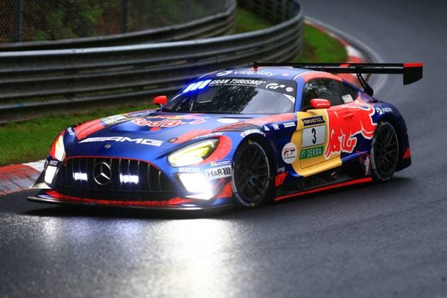 The Mercedes AMG GT3 Daniel Juncadella Jules Gounon Lucas Auer Max Verstappen Mercedes AMG Team Verstappen Racing of the Mercedes AMG Team Verstappen Racing fights its way through a corner on the Nordschleife of the Nürburgring on a wet track The vehicle wears the striking blue and red Red Bull livery with Gran Turismo and RAVENOL sponsorship as well as the starting number 3 The switched-on headlights are reflected in the rain-soaked asphalt, while the large rear wing provides downforce ADAC RAVENOL 24h Nürburgring Thursday Copyright: xspeedshotx