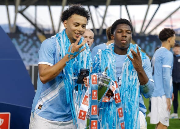 Manchester, England, 14th May 2026. Dante Headley (left) and Ryan McAidoo (right) of Manchester City celebrate with the FA Youth Cup trophy following the Manchester City U18 vs Manchester United, ManU U18 FA Youth Cup Final match at the Academy Stadium, Manchester. Picture credit should read: Cody Froggatt Sportimage EDITORIAL USE ONLY. No use with unauthorised audio, video, data, fixture lists, club league logos or live services. Online in-match use limited to 120 images, no video emulation. No use in betting, games or single club league player publications. SPI_080_CF_MANCHESTER_CITY_U18_V_MANCHESTER_UNITED_U18 SPI-4801-0078