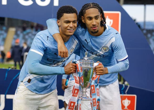 Manchester, England, 14th May 2026. Leke Drake (left) and Kaden Braithwaite (right) of Manchester City celebrate with the FA Youth Cup trophy following the Manchester City U18 vs Manchester United, ManU U18 FA Youth Cup Final match at the Academy Stadium, Manchester. Picture credit should read: Cody Froggatt Sportimage EDITORIAL USE ONLY. No use with unauthorised audio, video, data, fixture lists, club league logos or live services. Online in-match use limited to 120 images, no video emulation. No use in betting, games or single club league player publications. SPI_084_CF_MANCHESTER_CITY_U18_V_MANCHESTER_UNITED_U18 SPI-4801-0082