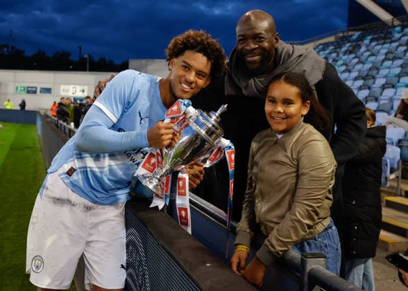 Manchester, England, 14th May 2026. Floyd Samba of Manchester City celebrate with the FA Youth Cup trophy with his father Christopher Samba following the Manchester City U18 vs Manchester United, ManU U18 FA Youth Cup Final match at the Academy Stadium, Manchester. Picture credit should read: Cody Froggatt Sportimage EDITORIAL USE ONLY. No use with unauthorised audio, video, data, fixture lists, club league logos or live services. Online in-match use limited to 120 images, no video emulation. No use in betting, games or single club league player publications. SPI_093_CF_MANCHESTER_CITY_U18_V_MANCHESTER_UNITED_U18 SPI-4801-0091