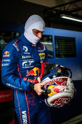 In the pits at the Nürburgring, a driver from Mercedes AMG Team Verstappen Racing prepares for his stint Wearing a white balaclava and the characteristic blue Red Bull racing overall with Sparco and Viaplay logos, he holds his Red Bull helmet in his hands The overall also features the Intercontinental GT Challenge logo as well as Michelin and RAVENOL sponsorship Verstappen Racing driver prepares in the pits Copyright: xMichaelxGelhardtx
