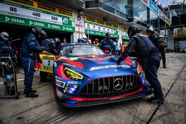 The Mercedes AMG GT3 with starting number 3 of the Mercedes AMG Team Verstappen Racing is at the pit stop in the pit lane of the Nürburgring The vehicle wears the characteristic blue and red Spider Man-inspired design with Red Bull and Gran Turismo sponsoring as well as the AMG logo on the hood Mechanics in dark team overalls work intently on the vehicle, while other team members coordinate the stop In the background, the pit display boards with the start numbers 80, 480 and 569 as well as the DEKRA and RAVENOL advertising banners can be seen Daniel Juncadella Jules Gounon Lucas Auer Max Verstappen Mercedes AMG Team Verstappen Racing Mercedes AMG GT3 3 from Verstappen Racing at the pit stop at the Nürburgring Copyright: xMichaelxGelhardtx