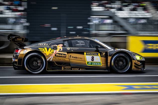 The Audi R8 LMS GT3 with starting number 8 of the JUTA Racing team passes the pit lane at the Nürburgring with a clear blur of movement The striking black and gold vehicle Alexey Veremenko Elia Erhart Vasilii Selivanov JUTA Racing bears the sponsors Veedol, Ravenol and Tradelinks prominently on the flank The filled grandstands of the Nürburgring can be seen in the background Audi R8 LMS 8 from JUTA Racing in the pit lane at the Nürburgring Copyright: xMichaelxGelhardtx
