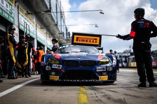 A blue BMW Z4 GT3 with the sponsors Pirelli, H R and KW is parked in the pit lane of the Nürburgring A mechanic with a helmet holds a Pirelli board next to the vehicle, while other team members and vehicles in the pit lane can be seen in the background The slogan WE VALUE PEOPLE can be read on the front apron, the vehicle bears the inscription W I S on the hood The starting number is not clearly legible on the vehicle BMW Z4 GT3 from W I S Racing in the pit lane at the Nürburgring Copyright: xMichaelxGelhardtx