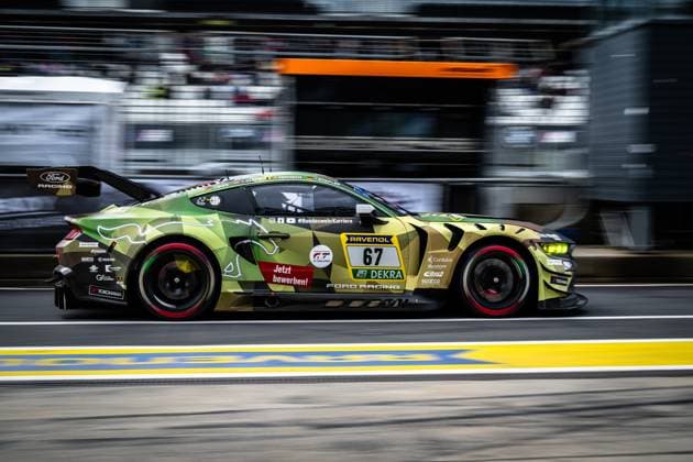 The Ford Mustang GT3 Arjun Maini Fabio Scherer Frank Stippler HRT Ford Racing from HRT Ford Racing drives through the pit lane of the Nürburgring at an impressive speed The vehicle wears a striking camouflage livery in green and earth tones with the BundeswehrKarriere lettering and the sponsors RAVENOL, DEKRA and Ford Racing The starting number 67 is clearly recognizable on the side of the vehicle Ford Mustang GT3 67 from HRT Ford Racing in the pit lane Copyright: xMichaelxGelhardtx
