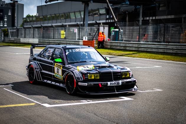The black Mercedes Benz 190E with starting number 61 from HWA Engineering Speed rolls through the pit lane at the Nürburgring The striking vehicle has a black and white design with eye-catching sponsors such as RAVENOL, DEKRA, H R and Hankook The broadband racer with rear spoiler and yellow headlights is a real eye-catcher in the field of drivers at the 24h Nürburgring 2026 Bruno Spengler Christian Gebhardt Evald Holstad Peter Ludwig HWA Engineering Speed Mercedes Benz 190E 61 from HWA Engineering Speed in the pit lane Copyright: xMichaelxGelhardtx