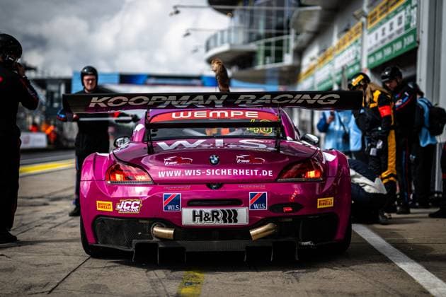 The magenta-colored BMW Z4 GT3 with the starting number 40 of the W I S Racing Team powered by Koopman Racing is parked in the pit lane of the Nürburgring The sponsor lettering KOOPMAN RACING is clearly legible on the rear wing, with the logos of WEMPE and W I S and the website www wis sicherheit de emblazoned below it Mechanics work on the right side of the vehicle, while other team members can be seen in the background The eye-catching vehicle also bears the sponsors H R, Pirelli and JCC Racing Frank Nikolaus Michael Funke Peter Posavac W I S Racing Team powered by Koopman Racing BMW Z4 GT3 40 from W I S Racing Team in the pit lane at the Nürburgring Copyright: xMichaelxGelhardtx