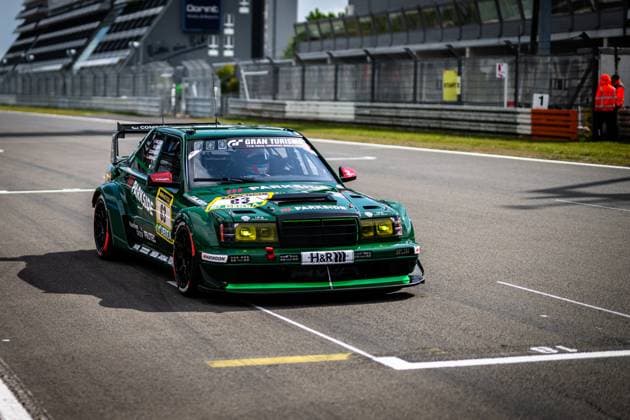 The dark green vehicle with the starting number 63 - a heavily modified Mercedes 190E - rolls through the pit lane at the Nürburgring The vehicle bears the sponsors Parkside, H R and Hankook as well as Gran Turismo lettering on the windshield In the background, track marshals in orange warning clothing and the start-finish grandstand can be seen Adam Adelson James Green Lance David Arnold Renger Van der Zande HWA Engineering Speed Mercedes 190E 63 from HWA Engineering Speed in the pit lane Copyright: xMichaelxGelhardtx