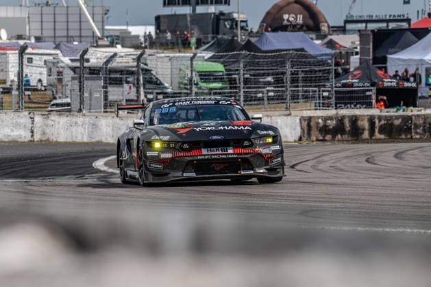 The Ford Mustang GT3 with the starting number 65 of the HRT Ford Racing team drives through a bend at the Nürburgring The black-painted vehicle bears the distinctive Yokohama and H R sponsors as well as the Gran Turismo lettering on the roof The yellow brake lights light up when turning in; barriers, spectator area and team tents can be seen in the background Colin Caresani David Schumacher Hubert Haupt Vincent Kolb HRT Ford Racing Ford Mustang GT3 65 from HRT Ford Racing at the Nürburgring Copyright: xMichaelxSchäferx
