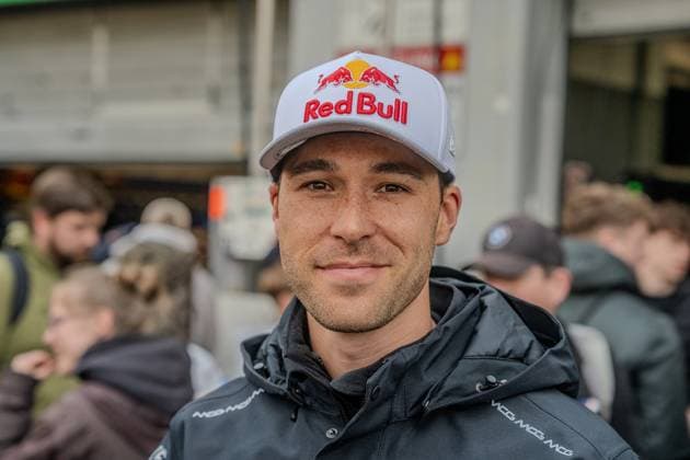 Kelvin van der Linde can be seen in the paddock at the Nürburgring wearing a Red Bull cap and an MCG team jacket Other people and team structures can be seen in the background, hinting at the lively atmosphere of the 24-hour race weekend Kelvin van der Linde in the paddock at the Nürburgring Copyright: xMichaelxSchäferx