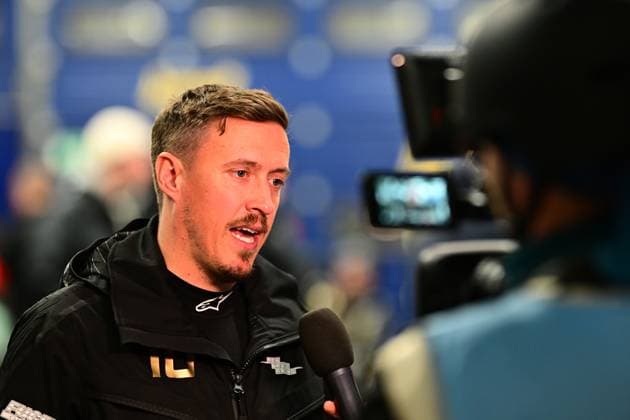 A rider in a black Alpinestars jacket with the number 10 gives an interview to a TV team A blue sponsor backdrop can be seen in the background The cameraman points the camera at the rider while a microphone protrudes into the picture The scene takes place in the paddock of the Nürburgring Rider interview at the 24h Nürburgring 2026 in the paddock Copyright: xMichaelxGelhardtx
