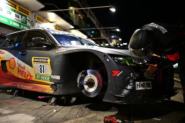 The car Connor de Phillippi Jens Klingmann Neil Verhagen Ugo de Wilde BMW M Motorsport from BMW M Motorsport stands in the pit lane of the Nürburgring during a night-time pit stop A mechanic works intently on the exposed front wheel, The brake disc and the wheel hub system are clearly visible The car bears the starting number 81 and is equipped with the sponsors Shell Helix, RAVENOL, DEKRA and H R The illuminated pit signs with the numbers 777 and 966 can be seen in the background BMW M4 GT4 81 Changing tires at night at the Nürburgring Copyright: xMichaelxGelhardtx