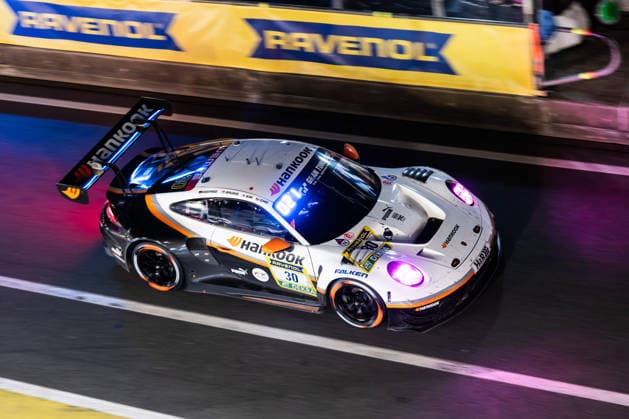The Porsche 911 GT3 R 992 Evo26 with starting number 30 from the Hankook Competition team with drivers Jongkyum Kim, Roelof Bruins, Steven Cho and Marco Seefried drives at night in the pit lane on the Nürburgring Grand Prix circuit during the 24-hour race Nürburg Rhineland-Palatinate Germany