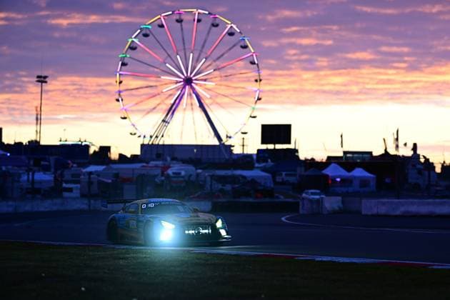 The Mercedes AMG GT3 Adam Christodoulou Christopher Lulham Marek Böckmann Mikaël Grenier PROsport Racing from PROsport Racing drives through the pit lane of the Nürburgring at dusk The headlights shine brightly in the falling night, while in the background the colorfully illuminated Ferris wheel and the dramatic sunset with purple-orange sky form an impressive backdrop The picture conveys the special atmosphere of the 24-hour race Mercedes AMG GT3 26 at sunset at the Nürburgring Copyright: xMichaelxGelhardtx