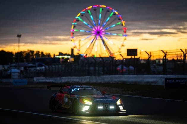 The Mercedes AMG GT3 from Red Bull with starting number 60 drives through the Nürburgring circuit at sunset In the background, an illuminated Ferris wheel shines in bright colors against a dramatic orange evening sky The vehicles switched-on headlights underline the dusky atmosphere of this impressive motorsport moment at the 24h Nürburgring 2026 Mercedes AMG GT3 60 at sunset at the Nürburgring Copyright: xMichaelxGelhardtx