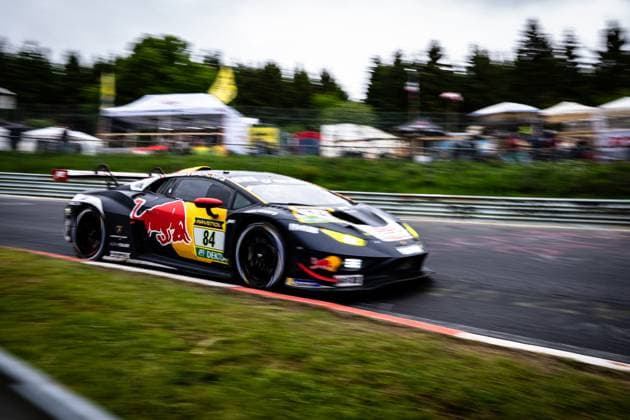The Lamborghini Huracán GT3 Luca Engstler Mirko Bortolotti Patric Niederhauser Red Bull Team ABT from Red Bull Team ABT drives through a bend at the Nürburgring at high speed The black and yellow vehicle with Red Bull livery and starting number 84 is captured in a dynamic panning shot, with the background blurred with spectators and tents in motion blur Clearly visible sponsors are Red Bull and RAVENOL Lamborghini 84 from Red Bull Team ABT at the Nürburgring Copyright: xMichaelxGelhardtx