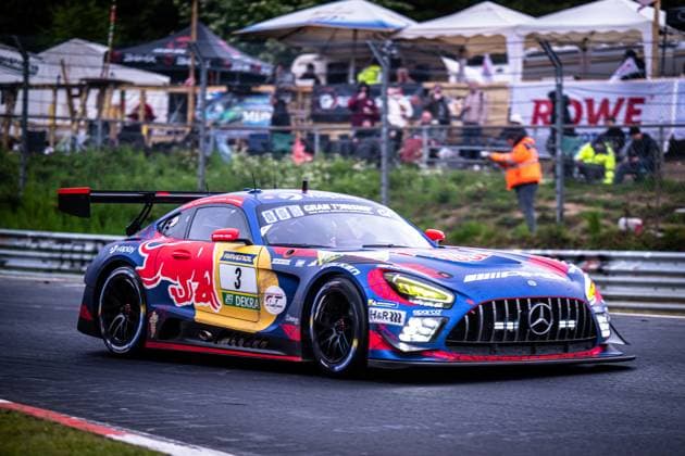 The Mercedes AMG GT3 3 from Mercedes AMG Team Verstappen Racing drives through a bend on the Nordschleife at the Nürburgring The vehicle wears the striking Red Bull livery in blue, red and yellow with a striking Red Bull logo on the side of the vehicle Sponsors such as RAVENOL, Viaplay, DEKRA and Gran Turismo can be seen prominently on the bodywork In the background, track marshals, spectators and hospitality tents can be seen, including a banner with the words ROWE Daniel Juncadella Jules Gounon Lucas Auer Max Verstappen Mercedes AMG Team Verstappen Racing Mercedes AMG GT3 3 from Verstappen Racing on the Nordschleife Copyright: xMichaelxGelhardtx
