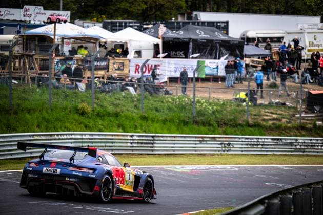 The Mercedes AMG GT3 from Mercedes AMG Team Verstappen Racing drives through a corner on the Nordschleife at the Nürburgring The vehicle Daniel Juncadella Jules Gounon Lucas Auer Max Verstappen Mercedes AMG Team Verstappen Racing wears the characteristic Red Bull livery in dark blue with the distinctive Red Bull logo on the side of the vehicle Sponsors such as H R and Multimatic are recognizable on the bodywork In the background, numerous spectators follow the racing action from a hill, A ROWE banner is attached to the barrier Mercedes AMG GT3 3 from Verstappen Racing on the Nordschleife Copyright: xMichaelxGelhardtx
