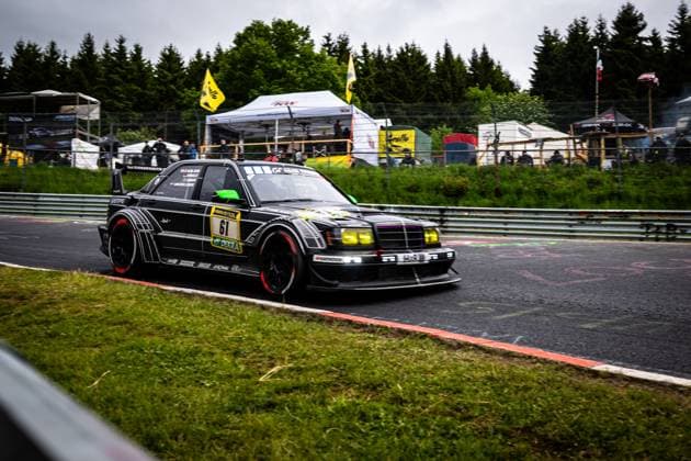 The striking black Mercedes Benz with starting number 61 from HWA Engineering Speed takes the bend at the Nürburgring The elaborately designed vehicle with its characteristic black paintwork, red brake discs and yellow headlights features an aggressive aerodynamic body Sponsors such as RAVENOL and DEKRA are clearly visible Spectators can be seen in the background, tents and yellow flags can be seen in the background, emphasizing the atmosphere of the 24h Nürburgring 2026 Bruno Spengler Christian Gebhardt Evald Holstad Peter Ludwig HWA Engineering Speed Mercedes Benz 61 from HWA Engineering Speed at the Nürburgring Copyright: xMichaelxGelhardtx