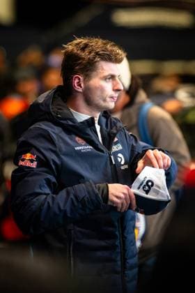 Max Verstappen stands in the paddock of the Nürburgring in the dark blue team jacket of Verstappen Racing with Red Bull logo and holds a white cap in his hands In the background you can see other people and the typical paddock atmosphere Max Verstappen in the paddock at the 24h Nürburgring 2026 Copyright: xMichaelxGelhardtx