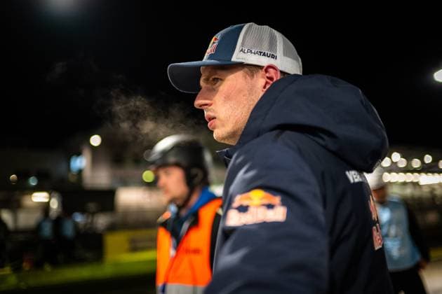 Max Verstappen from Mercedes AMG Team Verstappen Racing stands in the Nürburgring paddock at night He wears an AlphaTauri cap and a dark blue Red Bull jacket and looks intently to the side Another person with a helmet and orange vest can be seen in the background, the pit lane atmosphere is atmospherically lit Max Verstappen in the paddock at the 24h Nürburgring 2026 Copyright: xMichaelxGelhardtx