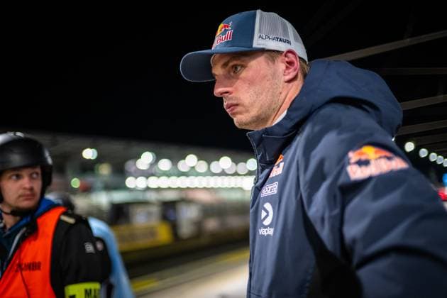 Max Verstappen from Mercedes AMG Team Verstappen Racing stands concentrated in the pit lane at the Nürburgring He wears a Red Bull AlphaTauri cap and a dark blue jacket with Red Bull and Viaplay logo The illuminated pits and a marshal in an orange vest can be seen in the background Max Verstappen in the paddock at the 24h Nürburgring 2026 Copyright: xMichaelxGelhardtx
