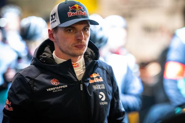 Max Verstappen can be seen in the paddock of the Nürburgring He is wearing the dark blue team jacket of Mercedes AMG Team Verstappen Racing with the logos of Red Bull, Sparco and Viaplay The Red Bull logo can also be seen on his cap Other people in team clothing can be seen blurred in the background Max Verstappen in the paddock at the 24h Nürburgring 2026 Copyright: xMichaelxGelhardtx