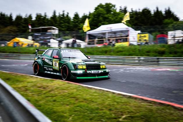 The dark green Mercedes Benz racing car with the starting number 63 from HWA Engineering Speed drives dynamically through a bend on the Nürburgring The vehicle bears eye-catching sponsor logos such as PARKSIDE and RAVENOL and is equipped with yellow tinted headlights and a striking rear wing The image was created using panning technology, which blurs the background with the yellow RAVENOL flags and the paddock area in the blurred bokeh Adam Adelson James Green Lance David Arnold Renger Van der Zande HWA Engineering Speed Mercedes Benz 63 from HWA Engineering Speed at the Nürburgring Copyright: xMichaelxGelhardtx