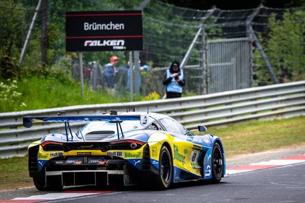 The McLaren 720S GT3 with starting number 69 from Doerr Motorsport passes the iconic Brünnchen section of the Nürburgring Nordschleife in blue and yellow The vehicle bears the sponsors Bitburger, RAVENOL and H R prominently on the bodywork Spectators and a marshal can be seen in the background, behind them the characteristic Brünnchen sign with Falken Tyres branding Ben Doerr Marvin Kirchhöfer Timo Glock Timo Scheider Doerr Motorsport McLaren 69 from Doerr Motorsport at the Brünnchen on the Nordschleife Copyright: xMichaelxGelhardtx