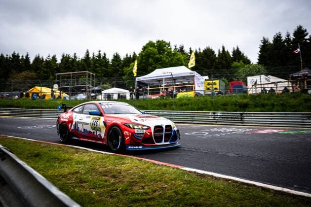 Aris Balanian Jeroen Bleekemolen Joshua Bednarski Peter Cate Tom Schütze Riller Schnauck powered by Cerny Motorsport from Riller Schnauck powered by Cerny Motorsport drives through a corner on the Nürburgring The red and white BMW M4 GT4 with the starting number 145 has sponsors such as NGK, Michelin, H R and DEKRA In the background, spectators, tents and yellow flags can be seen BMW M4 GT4 145 from Riller Schnauck powered by Cerny Motorsport on the Nordschleife Copyright: xMichaelxGelhardtx