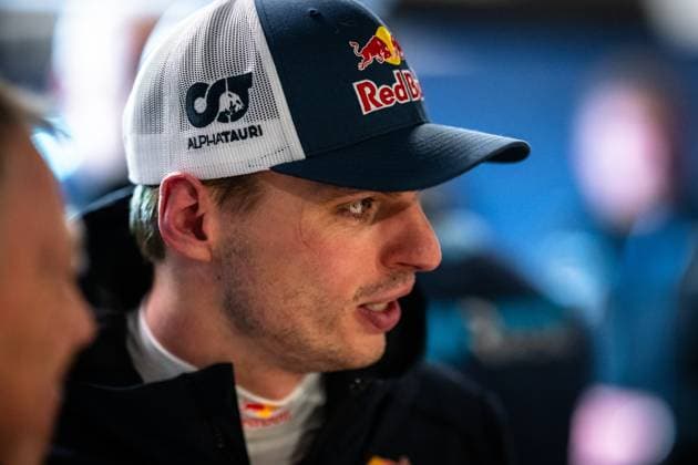 Max Verstappen can be seen in the paddock of the Nürburgring He is wearing a cap with Red Bull and AlphaTauri branding and a dark team jacket with Red Bull logo Other people can be seen blurred in the background The picture was taken as part of the ADAC RAVENOL 24h Nürburgring 2026 Max Verstappen in the paddock at the 24h Nürburgring 2026 Copyright: xMichaelxGelhardtx
