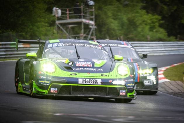 The Porsche 911 GT3 R Daan Arrow Dylan Pereira Patrick Assenheimer Tobias Müller 48 LOSCH Motorsport by BLACK FALCON from 48 LOSCH Motorsport by BLACK FALCON drives through a bend on the Nürburgrings Nordschleife with its headlights switched on The characteristic green and black painted vehicle carries sponsors such as Liqui Moly, H R, Goodyear, Fanatec and CODEX In the background, another Porsche 911 GT3 R closely follows Porsche 911 GT3 R 48 from LOSCH Motorsport by BLACK FALCON on the Nordschleife Copyright: xMichaelxGelhardtx