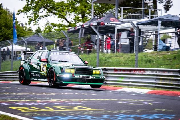 The dark green Mercedes 190E with the starting number 63 from HWA Engineering Speed drives through a bend on the Nürburgring The classic touring car racing car is decorated with sponsors such as Parkside, H R and Hankook and presents itself with yellow fog lights and a striking rear wing In the background, spectators and a black tent with the imprint BAMK can be seen Adam Adelson James Green Lance David Arnold Renger Van der Zande HWA Engineering Speed Mercedes 190E 63 from HWA Engineering Speed on the Nürburgring Copyright: xMichaelxGelhardtx