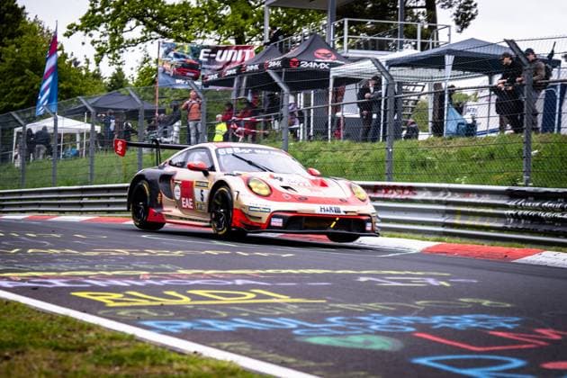 The Porsche 911 GT3 R from BLACK FALCON Team EAE with starting number 5 drives through a bend on the Nürburgring The car in the characteristic beige and red color scheme with EAE and H R sponsoring takes the curbs of the red and white curbs In the background, numerous spectators and photographers follow the race behind the fence. numerous spectators and photographers watch the race from behind the fence Colorful fan lettering adorns the asphalt of the Nordschleife Gabriele Piana Mike Stursberg Mustafa Mehmet Kaya Thomas Kiefer BLACK FALCON Team EAE Porsche 911 GT3 R 5 from BLACK FALCON Team EAE at the Nürburgring Copyright: xMichaelxGelhardtx