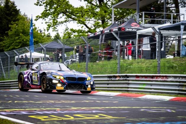 The BMW Z4 GT3 Frank Nikolaus Michael Funke Peter Posavac Volker Strycek W I S Racing Team powered by Koopman Racing from W I S Racing Team powered by Koopman Racing drives through a corner on the Nordschleife at the Nürburgring The car in dark blue with purple accents has the headlights switched on and shows the characteristic golden rims Sponsors such as RAVENOL, H R and Pirelli are recognizable on the vehicle In the background, spectators follow the race behind the safety net, a 24MX tent is also visible BMW Z4 GT3 40 from W I S Racing Team on the Nordschleife Copyright: xMichaelxGelhardtx