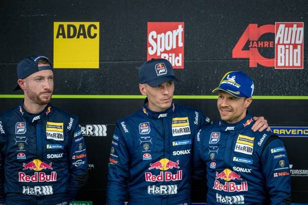 Three Red Bull Team ABT drivers present themselves at a press conference The drivers wear the characteristic dark blue overalls with Red Bull , RAVENOL , SONAX and Michelin sponsorship as well as ABT branding Media logos such as ADAC, Sport Bild and Auto Bild can be seen in the background Red Bull Team ABT drivers at the press conference for the 24h Nürburgring 2026 Copyright: xMichaelxGelhardtx